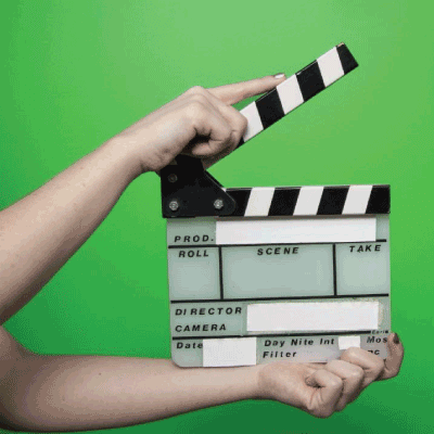 Arms with a clapperboard in front on a green screen.